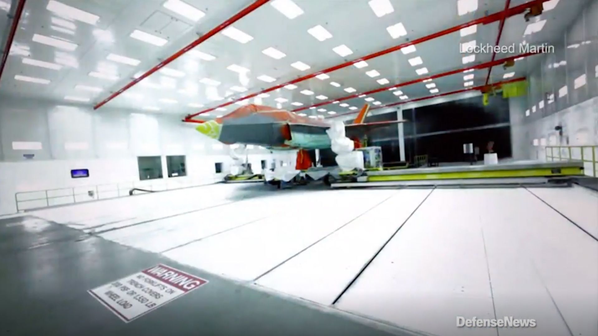 A wideshot of the F-35 Lightning II receiving low-observable coating from robotic paint systems as part of its manufacturing process. (Credit: Defense News)